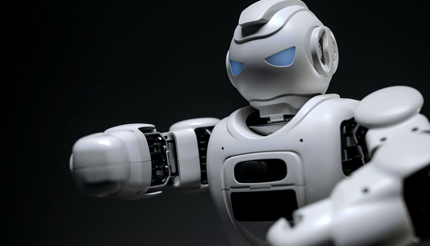 A sleek white AI robot with blue glowing eyes standing against a dark background, representing advanced artificial intelligence.