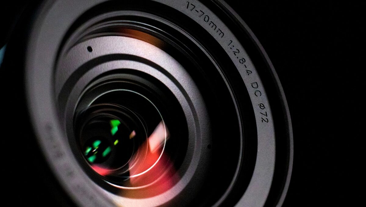 Detailed close-up shot of a 17-70mm professional camera lens showing glass reflections and aperture details.