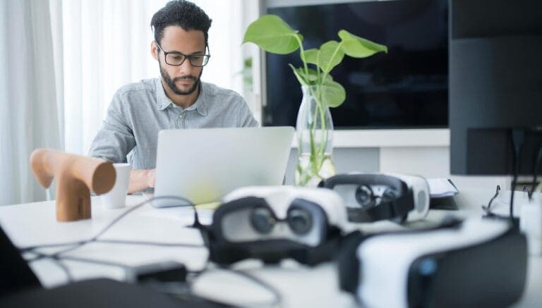 A professional tech expert working on a laptop with VR headsets on the desk representing technical skills in 2026.